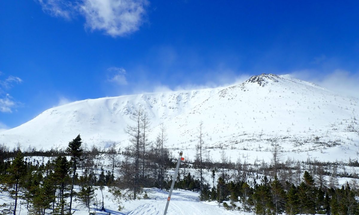 Is the wind picking up? Watch out for wind transport, which can add weight to slopes downwind (the side facing away from the wind). The thin clouds seen at the summit in this photo are actually plumes of snow being carried by the wind over the ridge. The slope where this snow will settle will become loaded and more prone to producing an avalanche.
